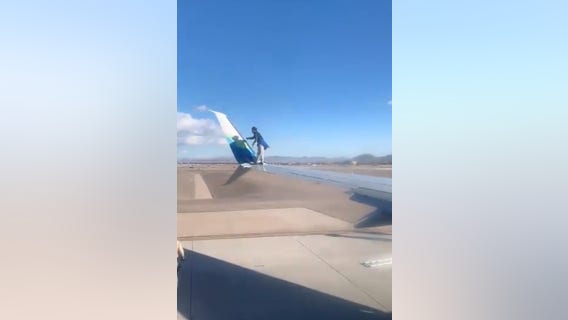 Man climbs onto commercial jet wing at Las Vegas airport, falls and gets arrested, videos show