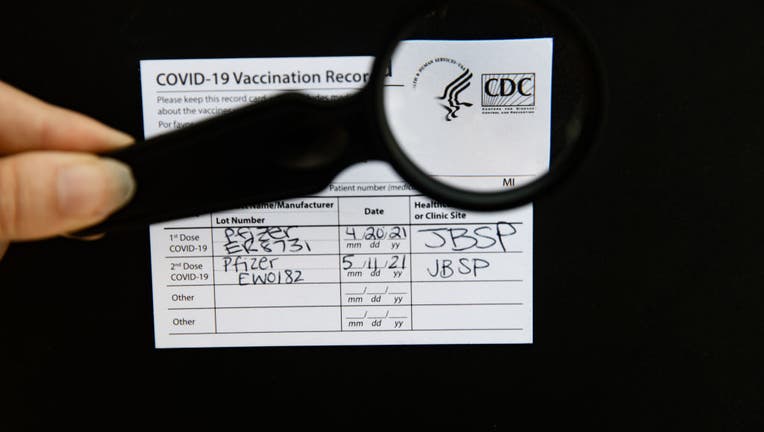 An authentic Covid-19 vaccination card, with CDC logo in magnifying glass