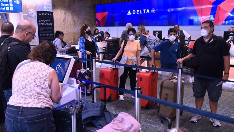 Travelers check in at a Delta Airlines counter at Orlando