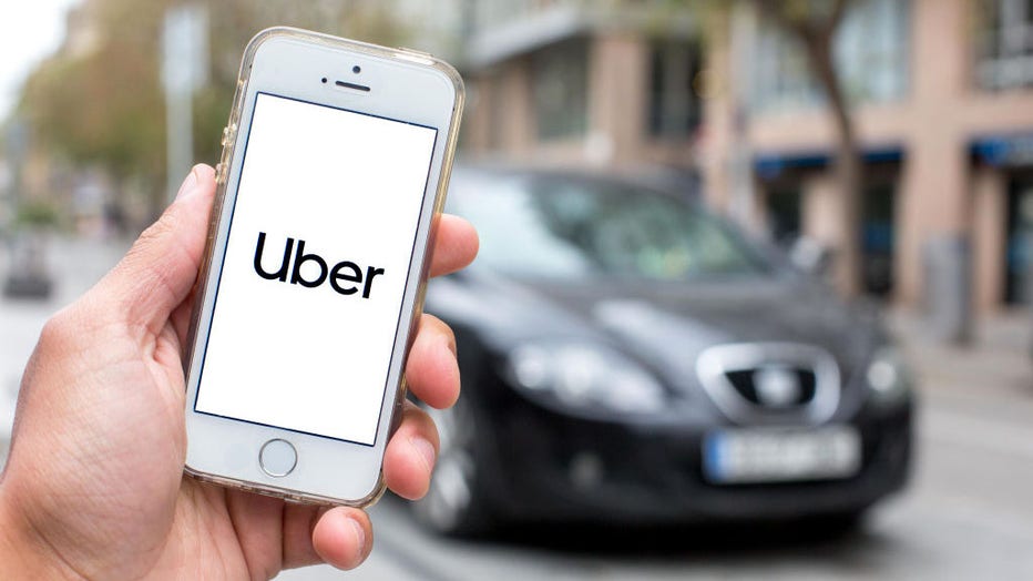 FILE - In this photo illustration, the Uber logo is seen displayed on a smartphone screen with a car in the background. (Photo Illustration by Thiago Prudencio/SOPA Images/LightRocket via Getty Images)