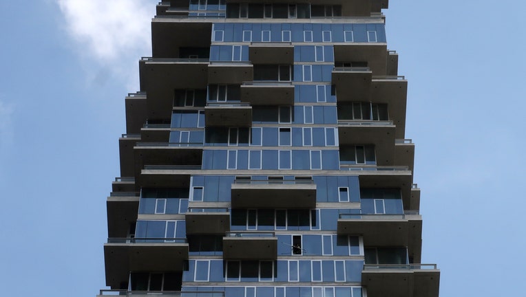 A cleaner washes a window in a condominium known as the 