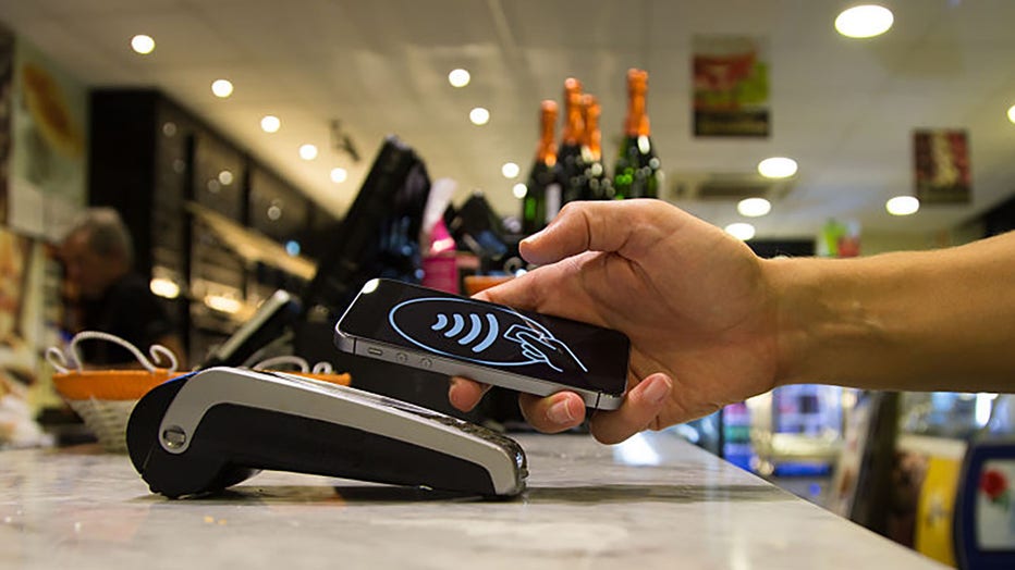 FILE - Man doing a contactless payment with smartphone at a bakery. (Credit: Getty Images)