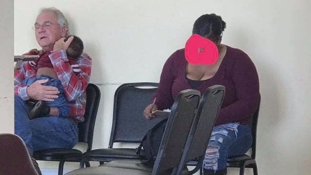 Man holds sleeping baby so mother can fill out patient paperwork, heartwarming moment goes viral