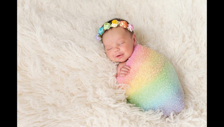 Smiling Newborn Baby Girl Wearing a Rainbow Colored Swaddle_1457797752996