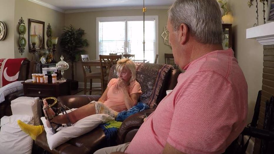 Woman sitting in chair with left ankle in a brace with husband looking