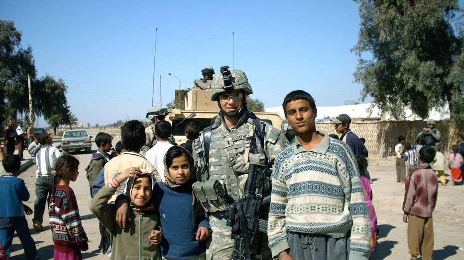 Garrett Cathcart poses with children in Iraq in 2006.