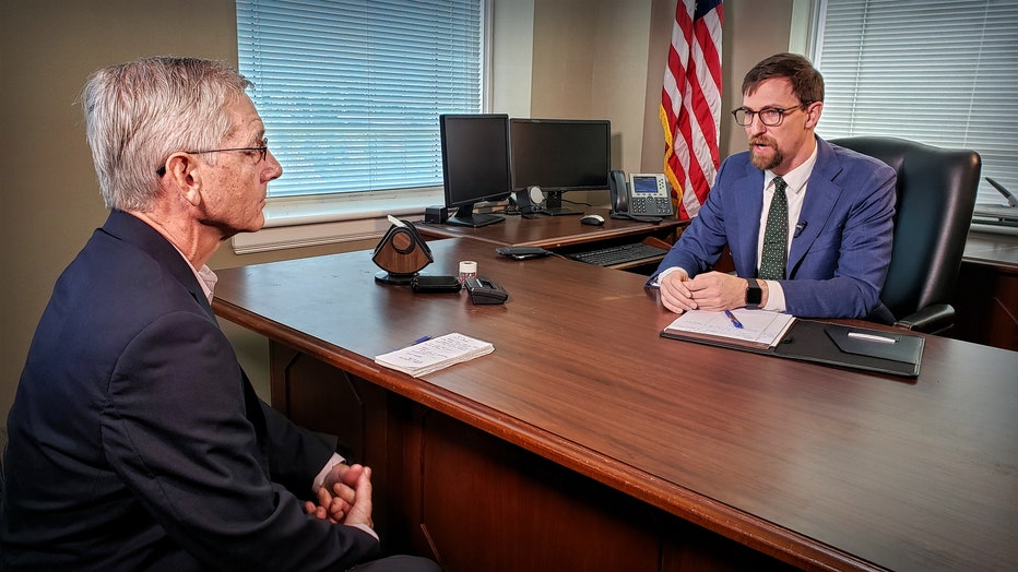 Randy sitting at desk talking to district attorney