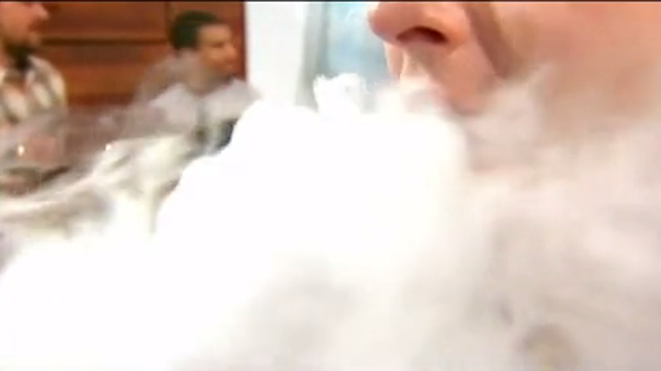 Man exhales vapor after using an e-cigarette device.