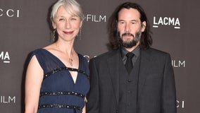 Keanu Reeves holds hands with artist on red carpet