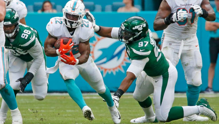 Mark Walton #22 of the Miami Dolphins runs past the attempted tackle of Nathan Shepherd #97 of the New York Jets during an NFL game on November 3, 2019 at Hard Rock Stadium in Miami Gardens, Florida. (Photo by Joel Auerbach/Getty Images)