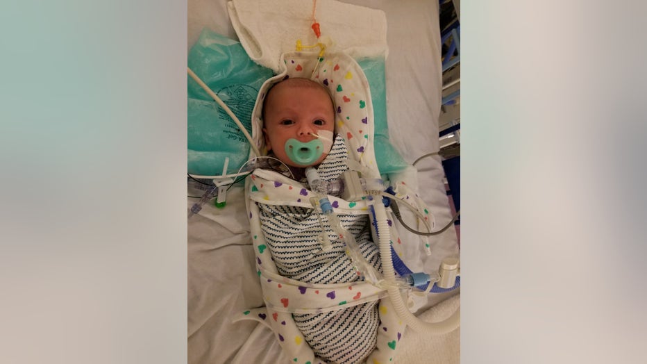 Baby lies swaddled in hospital bed.