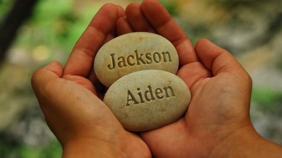 Hands hold stones carved with the names of couple's twin boys