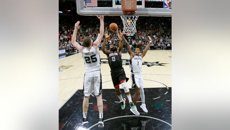 SAN ANTONIO, TX - DECEMBER 3: James Harden #13 of the Houston Rockets drives between Jakob Poeltl #25 of the San Antonio Spurs and Lonnie Walker #1 in the second half at AT&T Center on December 3, 2019 in San Antonio, Texas. NOTE TO USER: User expressly acknowledges and agrees that, by downloading and or using this photograph, User is consenting to the terms and conditions of the Getty Images License Agreement. (Photo by Ronald Cortes/Getty Images)