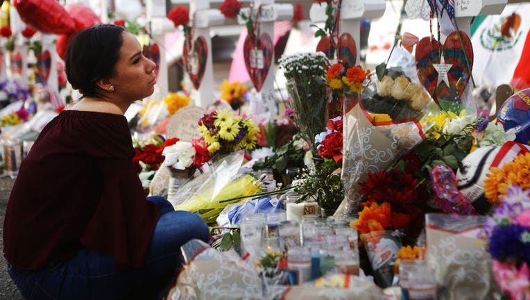 A woman stands by a growing memorial set up outside of a Walmart in El Paso, Texas, where 22 people were killed in a mass shooting.