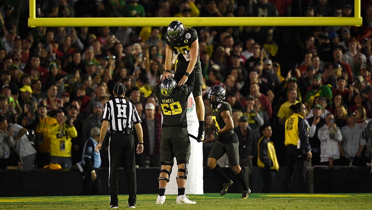 PASADENA, CALIFORNIA - JANUARY 01: Justin Herbert #10 of the Oregon Ducks celebrates with Penei Sewell #58 after scoring a 30 yard touchdown against the Wisconsin Badgers during the fourth quarter in the Rose Bowl game presented by Northwestern Mutual at Rose Bowl on January 01, 2020 in Pasadena, California. (Photo by Kevork Djansezian/Getty Images)