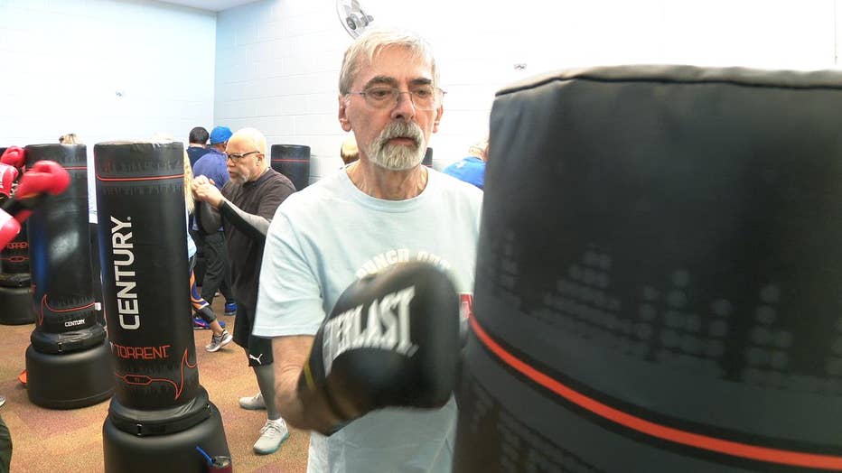 Man wearing boxing gloves punches bag