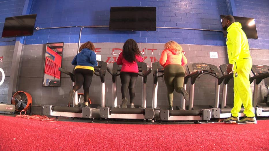 Women run on treadmills in a gym.