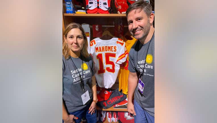 Angie and Jake Downs pose in front of football jersey