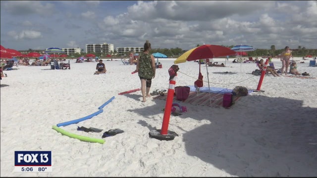 Beachgoers draw circles in the sand, use pool noodles to create social distance