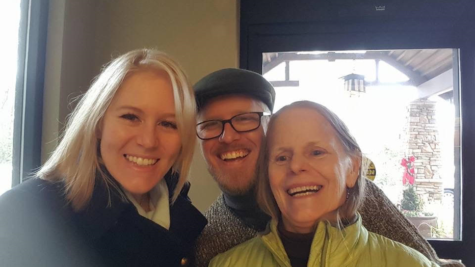 Woman smiles while her daughter and son pose for a photo with her.