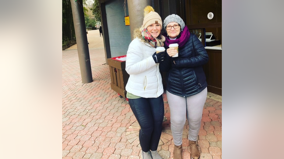 Women in winter coats hug outside a coffee store.