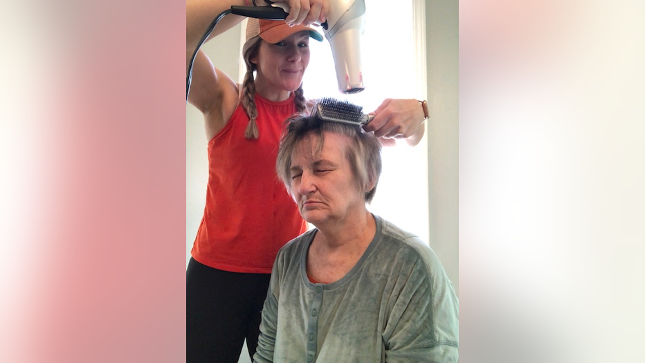 Women blowdries her mother's hair at home.