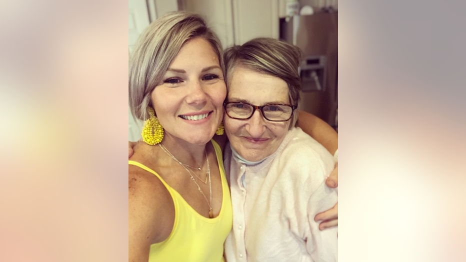 Young woman hugs her mother, who is smiling.