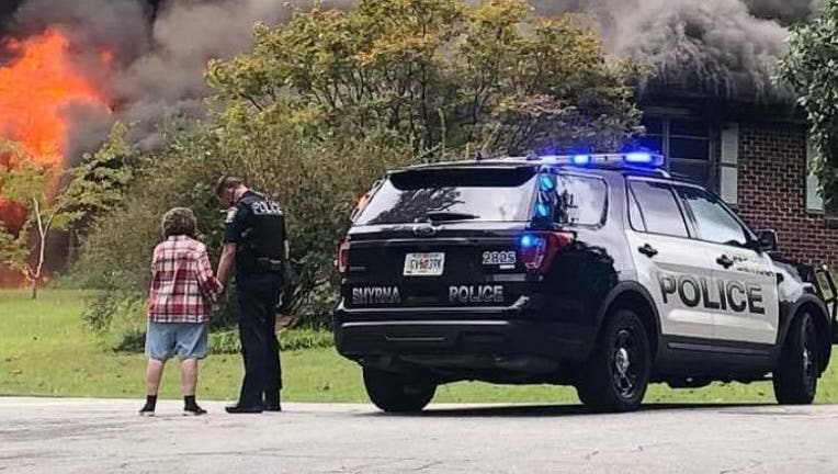 SPD Officer T. Melvin was captured comforting and praying with the victim of a house fire September 25, 2020 (Smyrna Police Department)