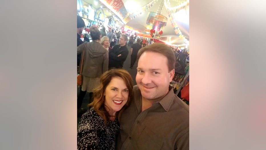 Woman hugs husband while posing at a party or festival.