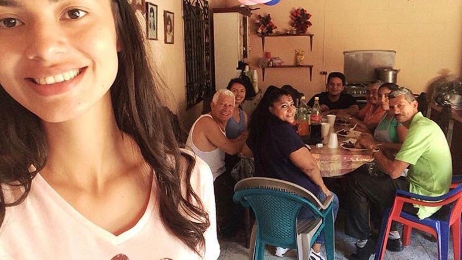 Smiling members of a family sit around a table, at a celebration.