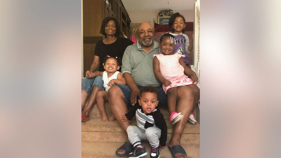 Man and wife sit surrounded by grandchildren