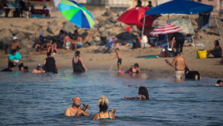 Amid a heat wave, Labor Day weekend beach-goers take to the cool ocean waters at the Santa Ana River County Beach River Jetties