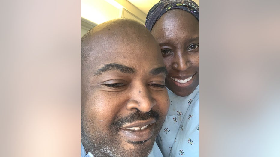 Couple in hospital gowns hugs while taking a selfie.