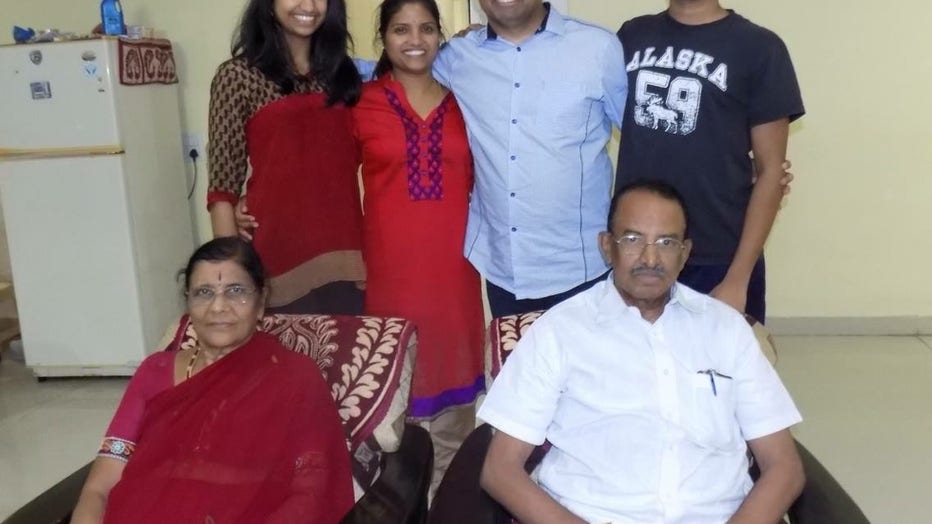 A doctor and his wife, son and daughter stand behind his parents, who are sittingin chairs. 