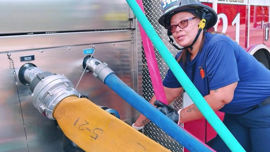 Woman in firefighter equipment poses during training.
