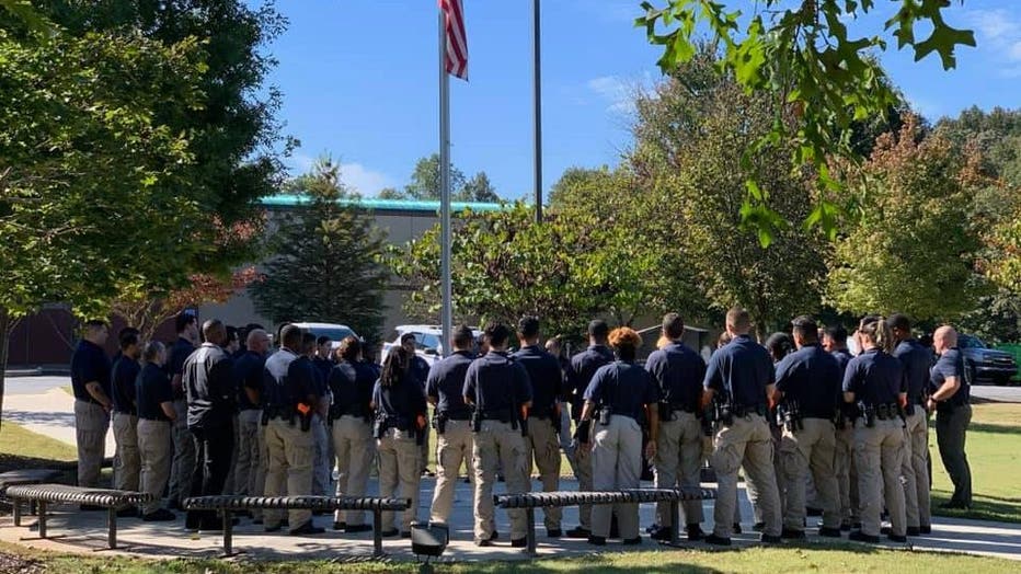 Recruits and fellow officers stand around a memorial to fallen Gwinnett County police officers on Oct. 20, 2021.