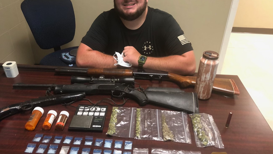 Officer Dylan Harrison poses with some of the drugs seized during a raid he participated in as a member of the Oconee Drug Task Force.