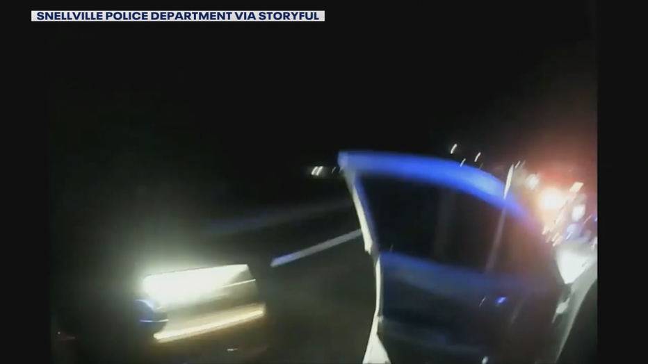 Bodycam video released by Snellville police show the blurry headline of a passing car that nearly struck an officer during a traffic stop on Sept. 29, 2021.