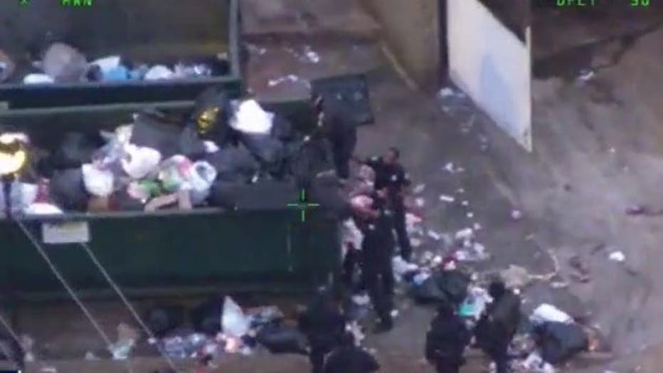 Atlanta police officers sift through garbage to pull a kidnapping suspect found by the air unit hiding in a dumpster on Jan. 17, 2022.