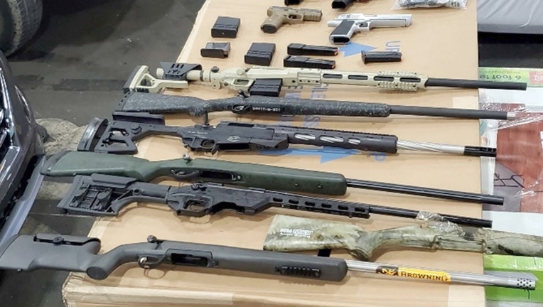 A photo introduced as evidence in USA v. Nihad Al Jaberi includes nine firearms from a shipment interdicted in the Port of Savannah and reassembled, along with other firearms removed during a search of the defendant’s residence.