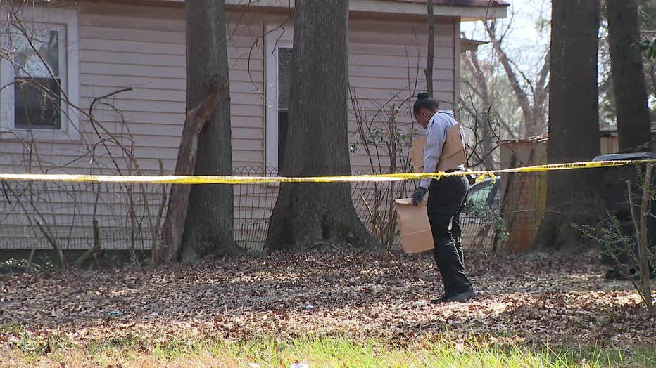 Investigators canvass the area where a body was found next to a vacant home in East Point on Feb. 12, 2022.
