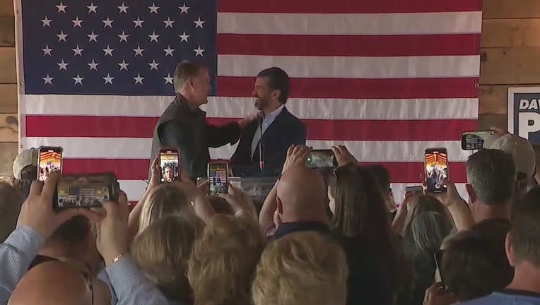 Former Sen. David Perdue shakes the hand of the former president's son, Donald Trump, Jr. during a campaign stop in Cumming on March 7, 2022.