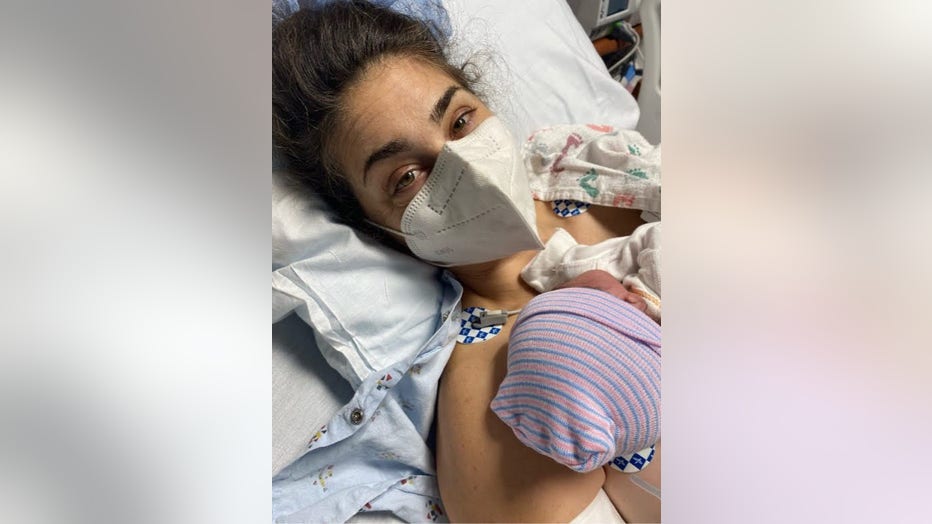 Woman wearing a mask embraces her newborn baby in the hospital.