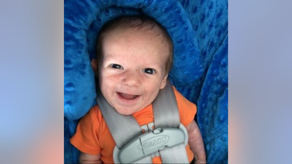 Newborn baby in car seat smiles up at the camera