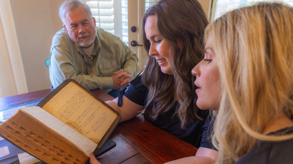 Man sits around table with his daughters. The women read from an old family Bible, where their grandmother kept a journal after her son's 1972 kidney transplant.