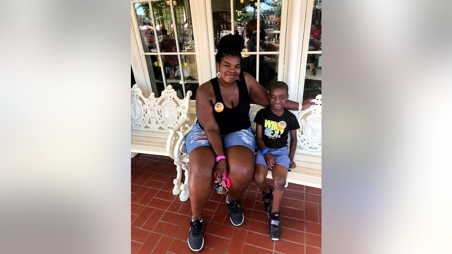 A mother and her 5-year-old son sitting on a bench at Disney World.  Both are smiling.