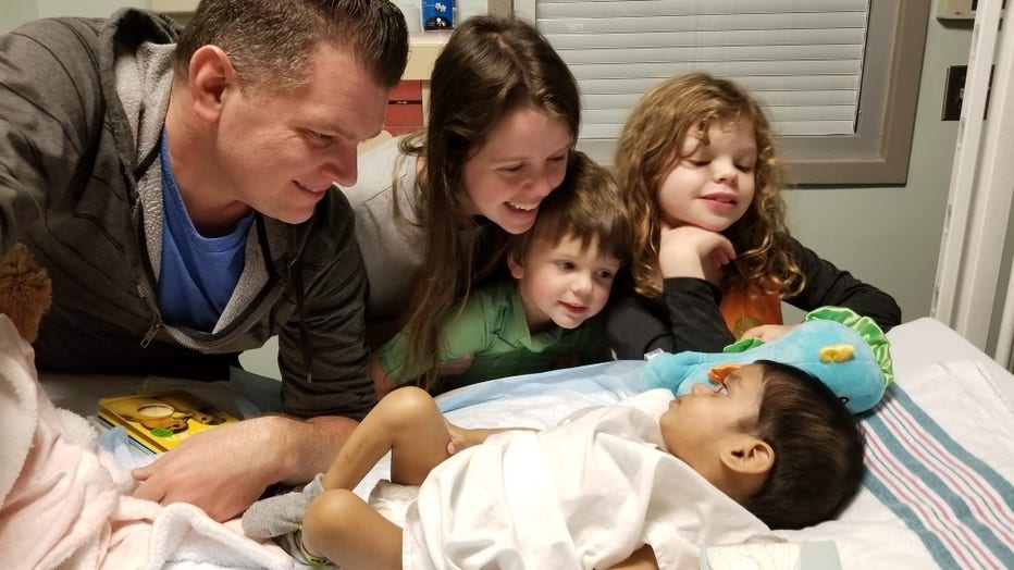 A toddler looks up at her family from a hospital bed shortly after her adoption. 