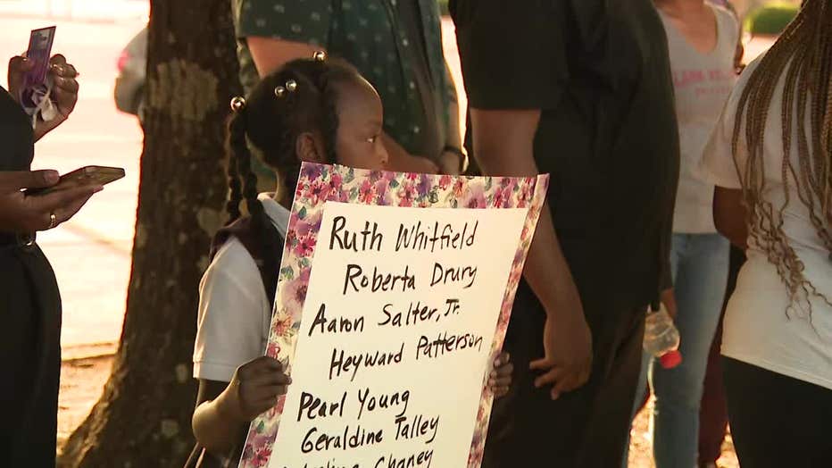 A young girl holds the names of those killed over the weekend in a mass shooting at a Buffalo grocery store during a vigil in DeKalb County on May 17, 2022.