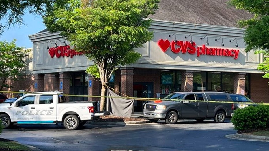 A sheet blocks the view of the victim of a deadly shooting in front of a Peachtree City drug store on May 4, 2022.