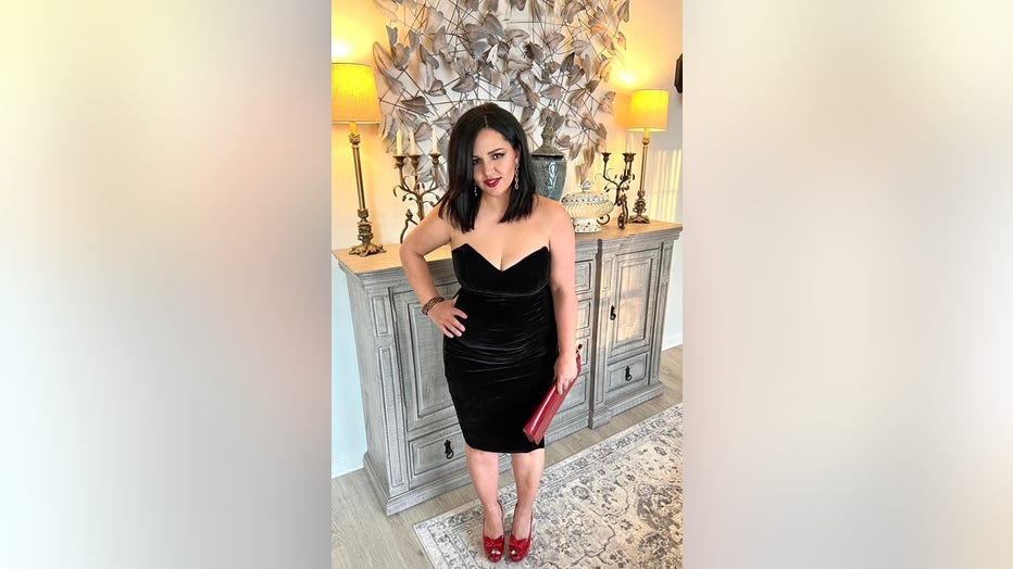 Woman in strapless dress poses in front of fireplace .